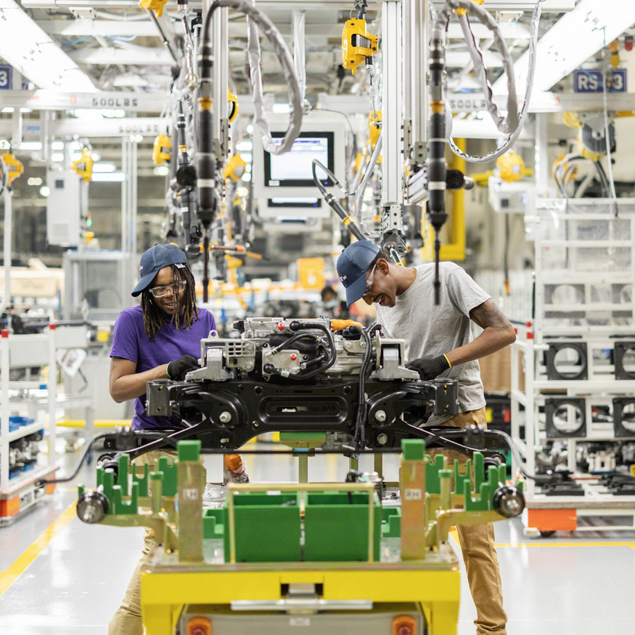 Two technicians assembling equipment on a factory line